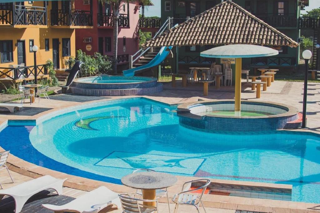 - une piscine avec un toboggan, des tables et des chaises dans l'établissement Costa Marlin Hotel, à Guriri