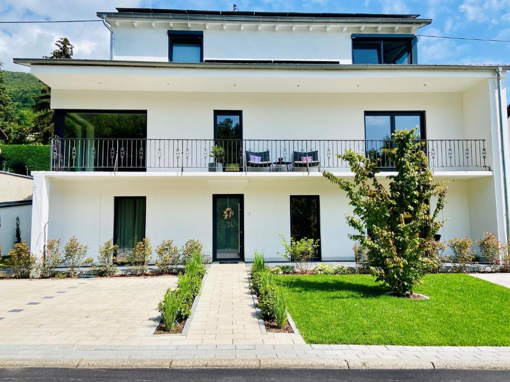 a white house with a balcony at HALBSTÜCK - Ferienwohnungen am Kropsbachpark in Sankt Martin