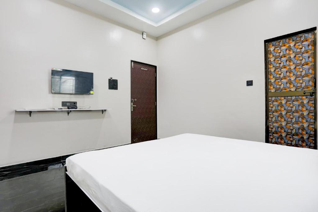 a white room with a bed and a door at OYO Hotel Raj Guest House in Akola
