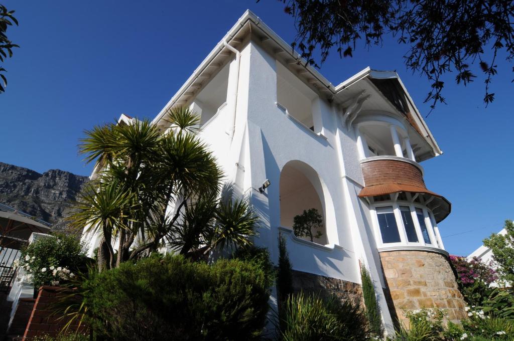 a white church with palm trees and mountains in the background at Abbey Manor Luxury Guesthouse in Cape Town