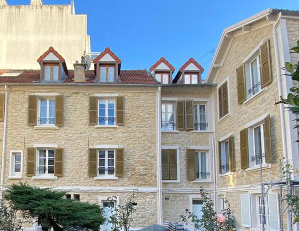 un gran edificio de ladrillo con ventanas laterales. en L'académie de Clémence, Guest House Paris-Roland-Garros en Boulogne-Billancourt