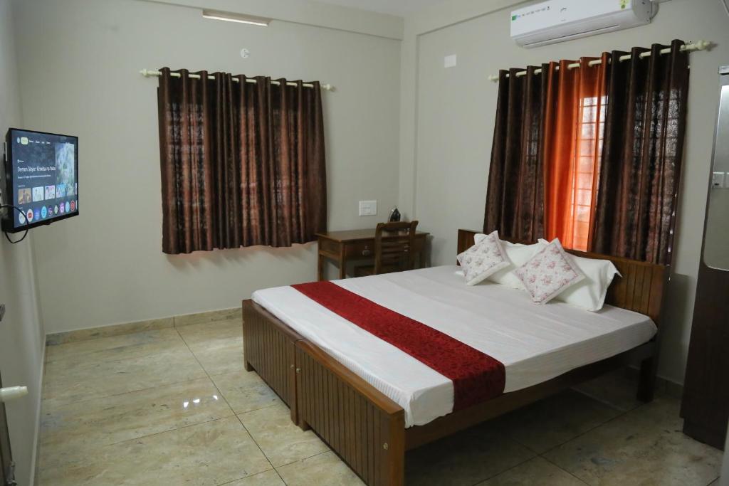 a bedroom with a bed and a tv in it at NR HEAVENZ Near Rajagiri Hospital in Alwaye