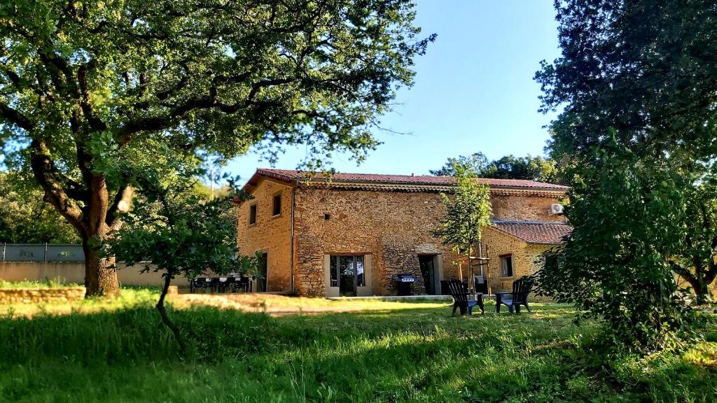 un ancien bâtiment en briques dans un champ arboré dans l'établissement Mas Corsin, à Piolenc