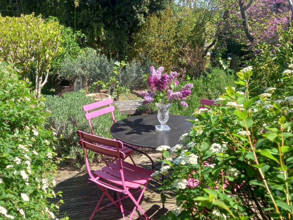 une table avec deux chaises et un vase de fleurs dans l'établissement Appartement T2 La campagne en ville, à Nîmes