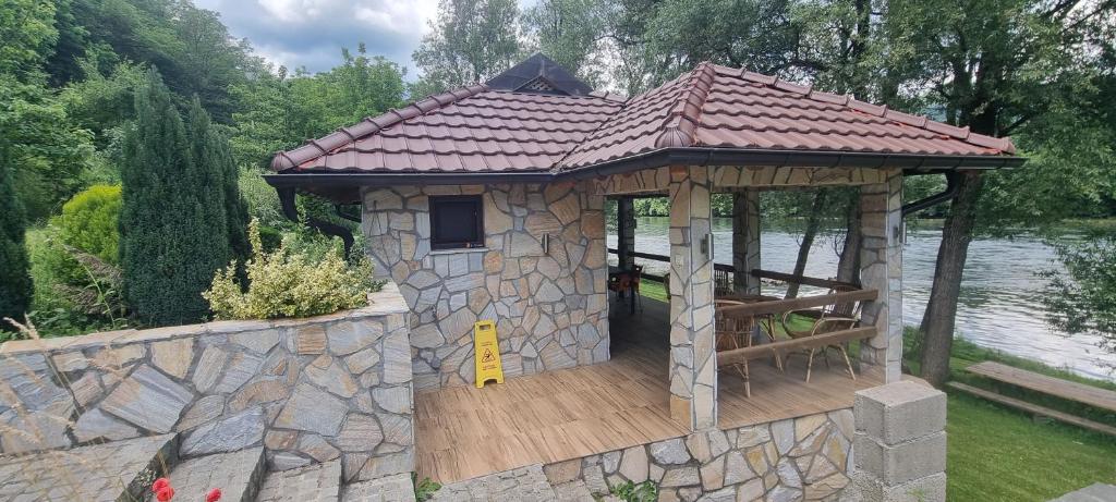 a gazebo on a stone wall next to a lake at Apartmani Kriva Drina in Okletac