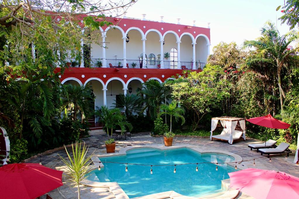 a swimming pool with umbrellas in front of a building at VILLA MERIDA BOUTIQUE HOTEL - Adults Only in Mérida