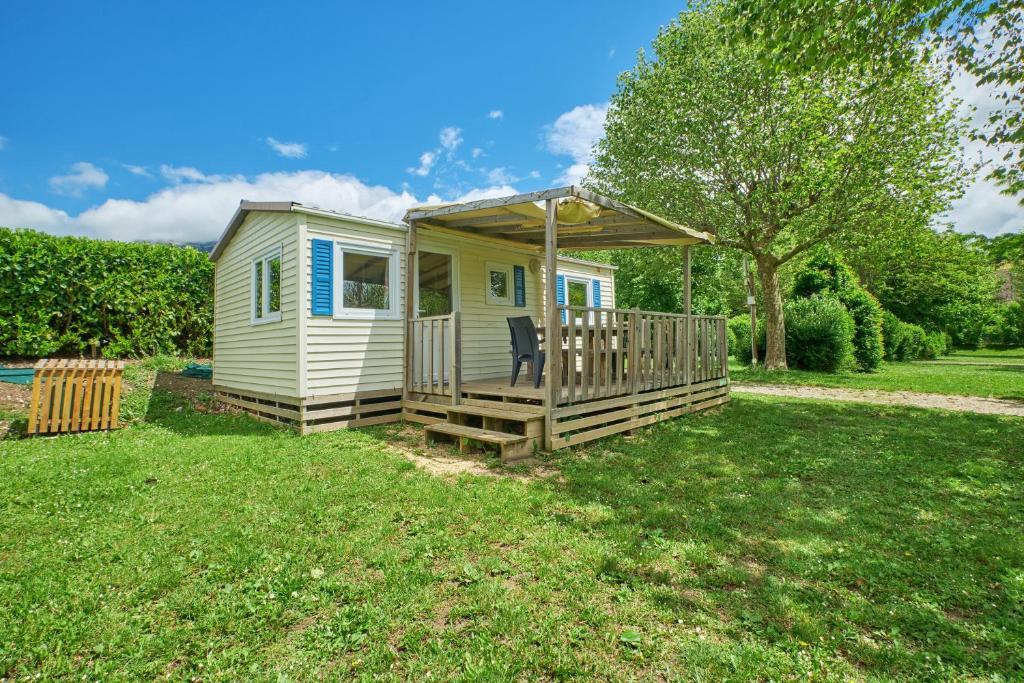 une petite maison avec une terrasse couverte et un kiosque dans l'établissement Mobil Home 5 personnes 210, à Mens