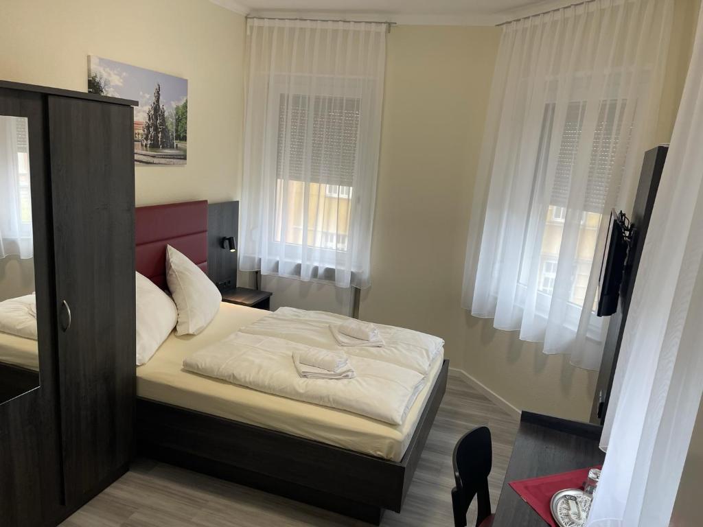 1 dormitorio con 1 cama con sábanas blancas y ventanas en Hotel König Humbert, en Erlangen
