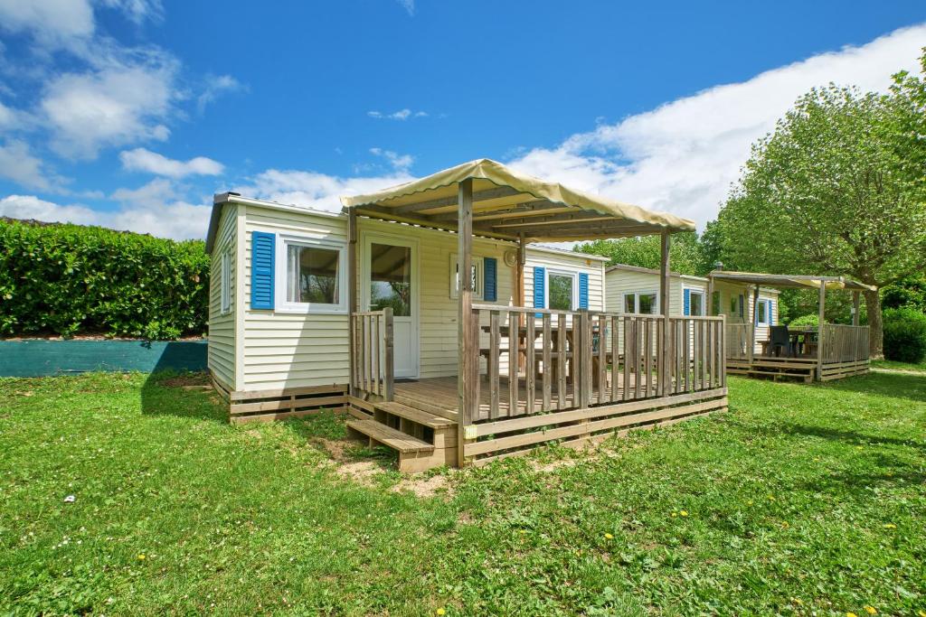 a tiny house with a deck and a gazebo at Mobil Home 5 personnes 209 in Mens