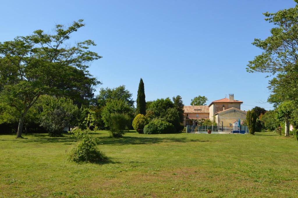 um campo de relva com uma casa ao fundo em Cinégîte du jardin aux étoiles - Proche de Saint Emilion em Saint-Pey-de-Castets