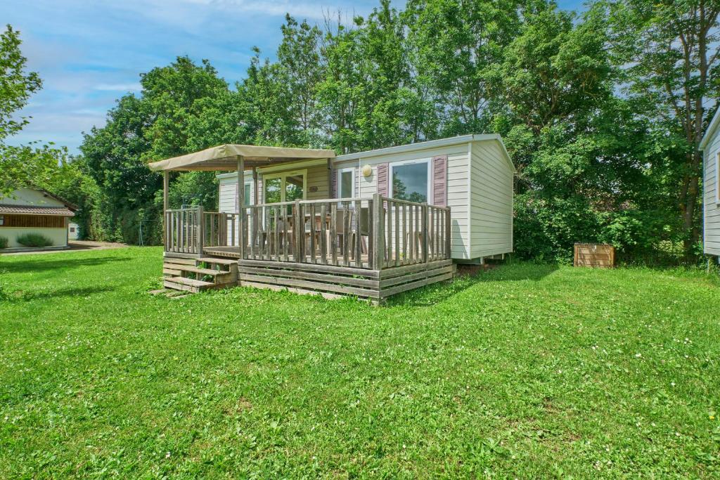 une petite maison avec une terrasse dans une cour dans l'établissement Mobil Home 6 personnes 205, à Mens