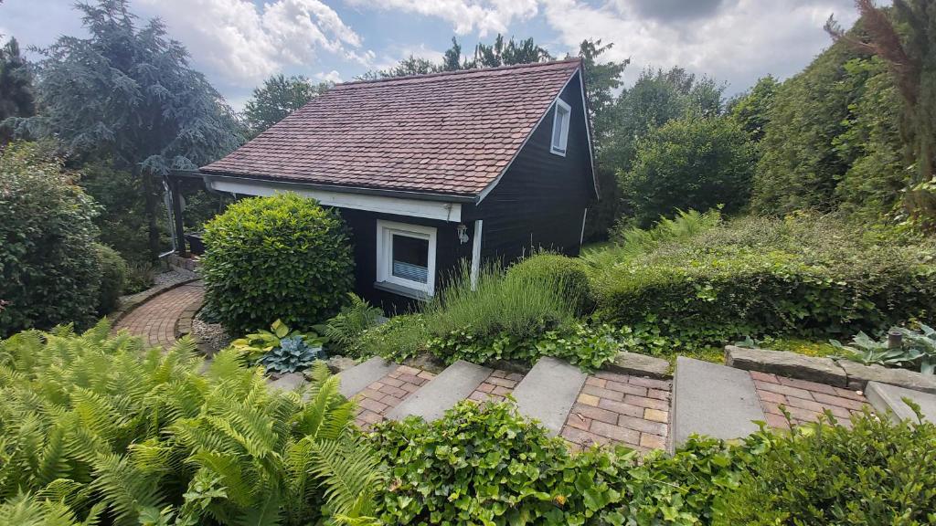 a small black house in the middle of a garden at Ferienhaus zur Dorfbachklamm in Altendorf