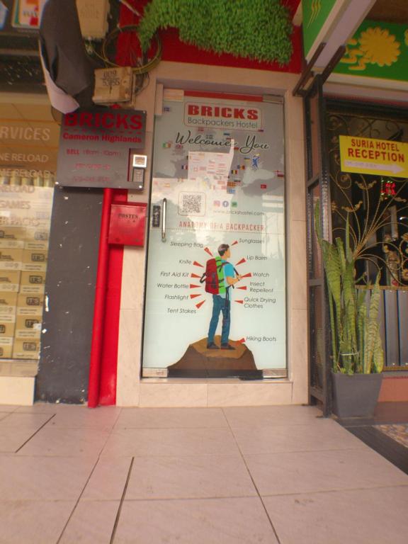 a store front with a picture of a man on the window at BRICKS Cameron Hostel in Tanah Rata