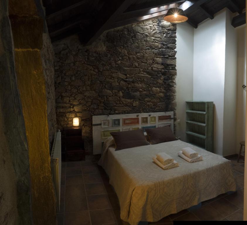 Hotel Rural Bermellar في Bermellar: غرفة نوم بسرير وجدار حجري