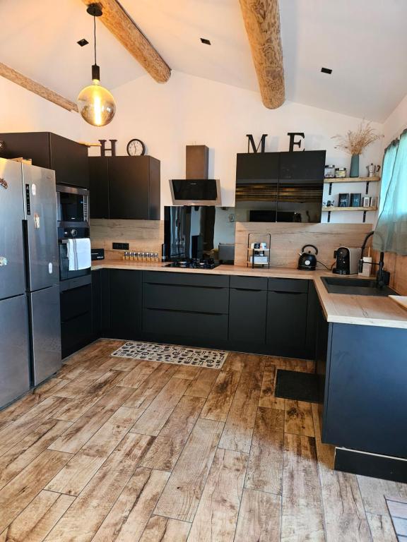 une cuisine avec des armoires noires et un plancher en bois dans l'établissement Maison col de varra, à Porto-Vecchio