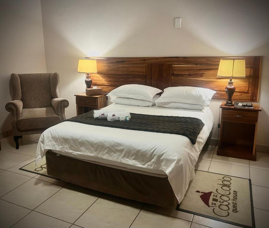 a bedroom with a large bed and a chair at Casa Calida Guest House in Upington