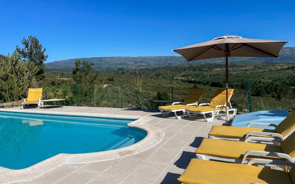 a swimming pool with chairs and an umbrella at Quinta da Estrela in Ponte Nova