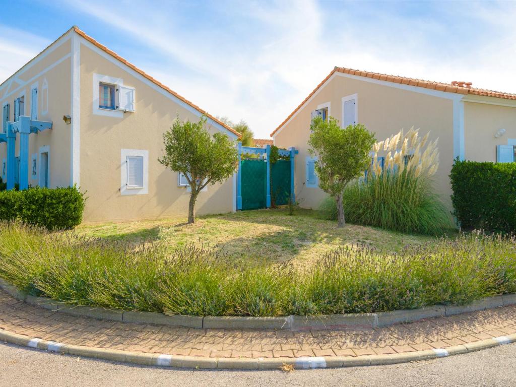 ein Haus mit blauen Türen und Bäumen im Hof in der Unterkunft Lagrange Vacances Le Scarlett et Les Soleillades in Palavas-les-Flots