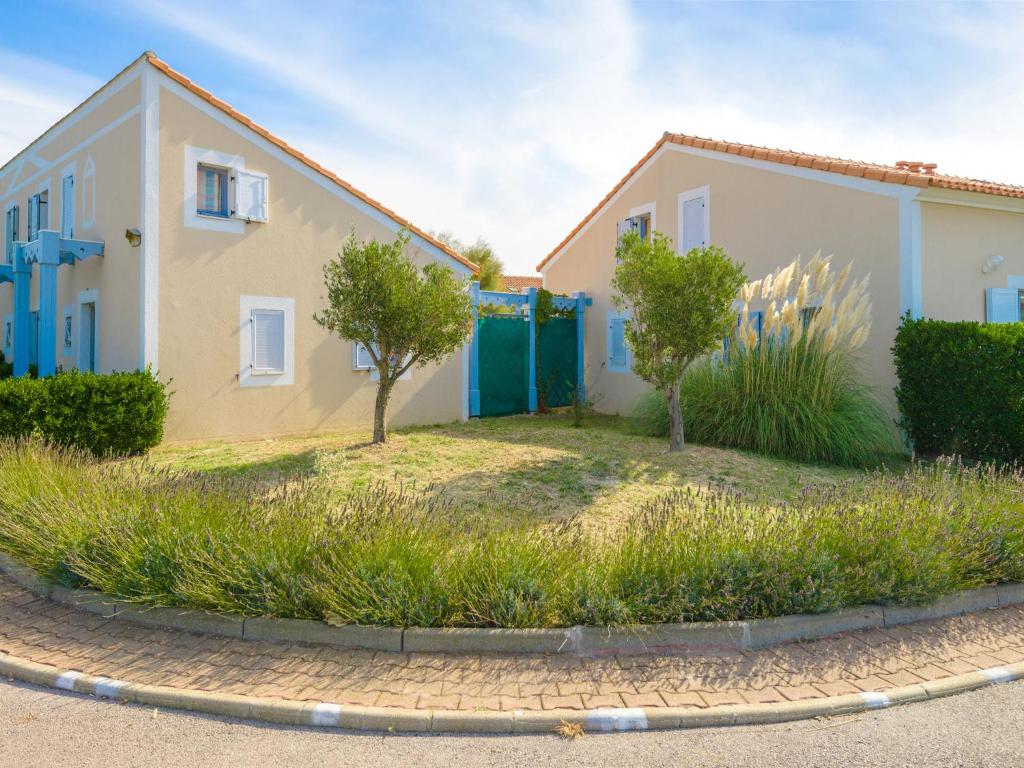 a house with blue doors and trees in a yard at Lagrange Vacances Le Scarlett et Les Soleillades in Palavas-les-Flots