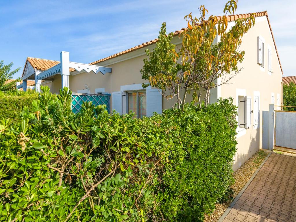 a house with a hedge in front of it at Lagrange Vacances Le Scarlett et Les Soleillades in Palavas-les-Flots