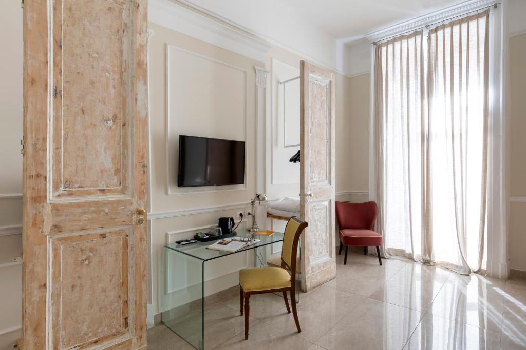 Pokój z biurkiem, telewizorem i drzwiami w obiekcie Napolit'amo Hotel Principe w mieście Neapol
