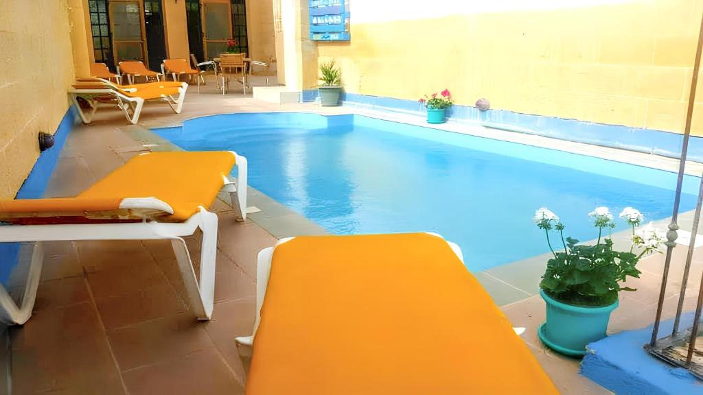 una piscina con due panchine gialle accanto ad essa di 3 bedrooms villa with sea view private pool and enclosed garden at Iz Zebbug a Qala