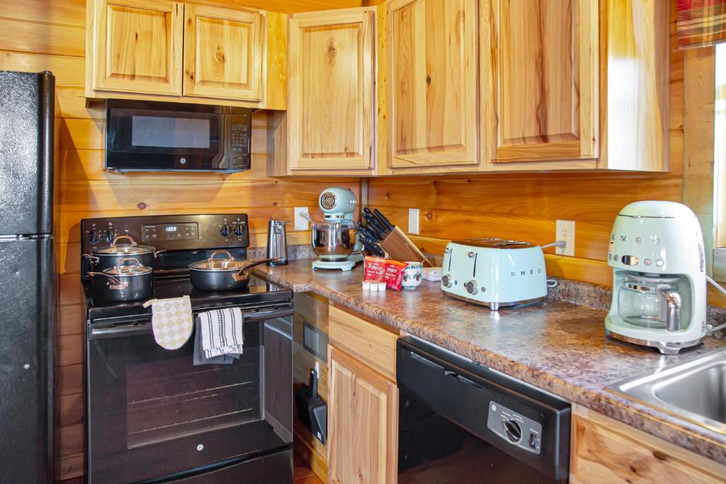 eine Küche mit Holzschränken und einem Backofen mit schwarzem Kochfeld in der Unterkunft Cabin In The Smokeys in Gatlinburg