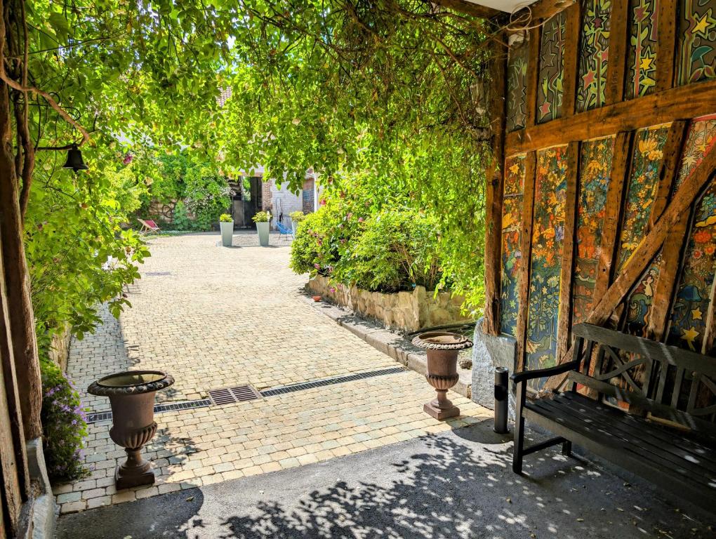 a bench sitting on a brick walkway with trees at Le Relais du Beffroi & SPA in Saint-Riquier
