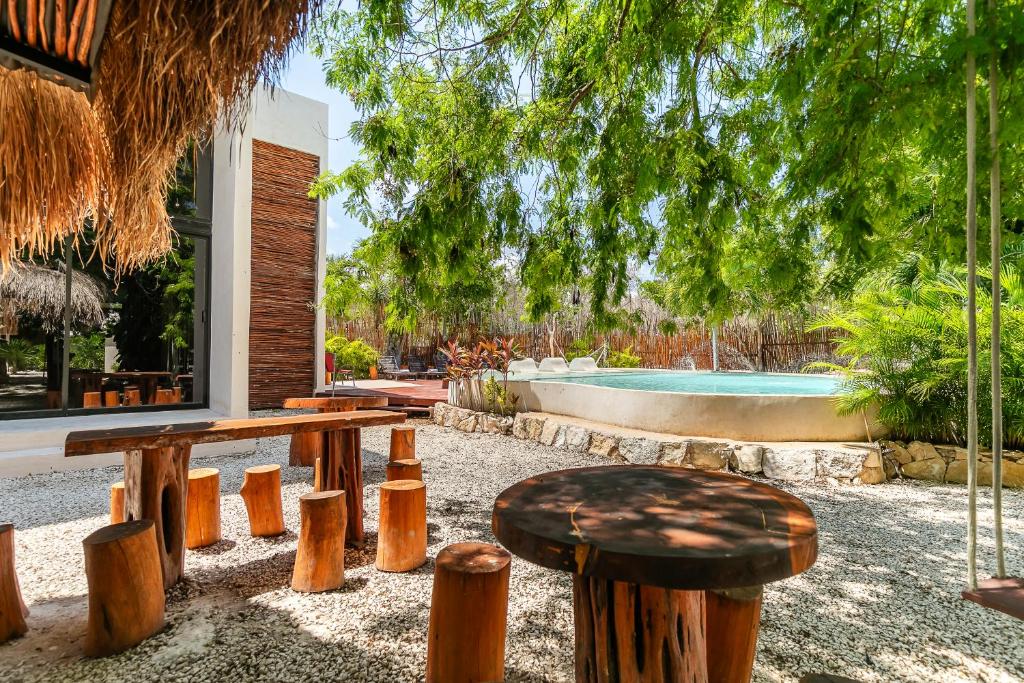 a patio with benches and a table and a pool at Xhule Tulum in Tulum
