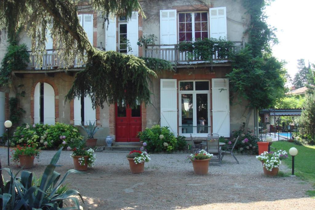 a house with a red door and potted plants at Villa du Canal in Toulouse