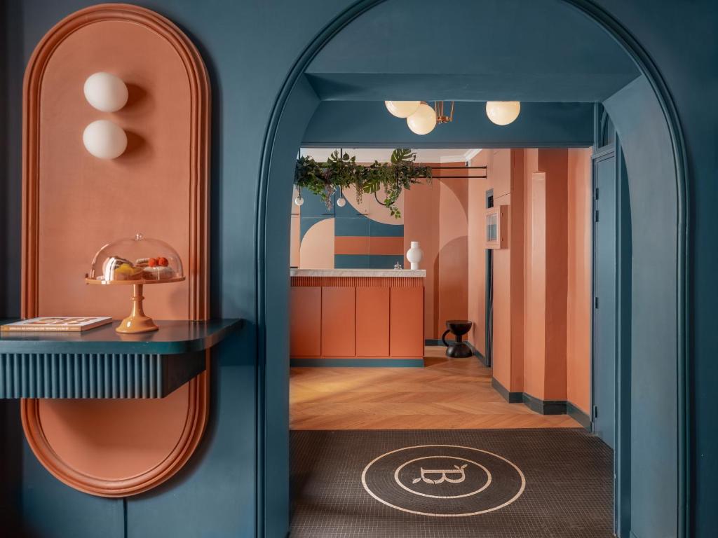 einen Flur mit einer gewölbten Tür in einen Raum mit Orange in der Unterkunft Hôtel Biskui in Levallois-Perret