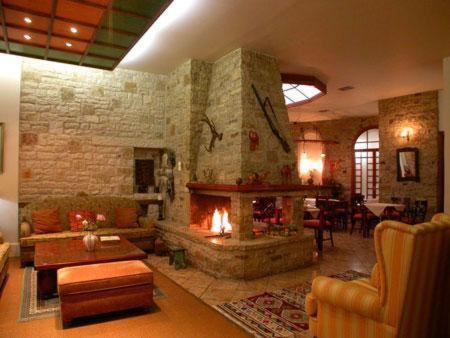 a living room with a fireplace and a stone wall at Hotel Elvetia in Karpenisi