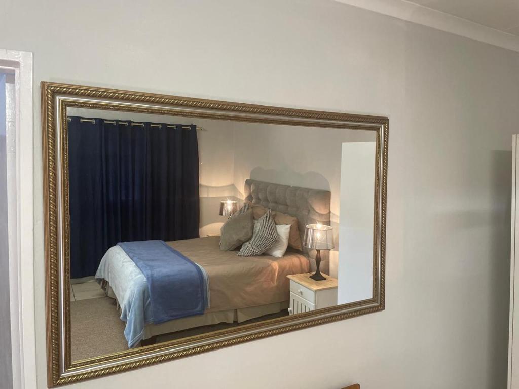 a mirror on a wall with a bed in a room at Pringle Cottage in Benoni