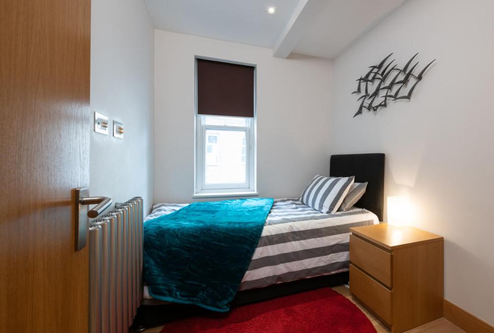 a small bedroom with a bed and a window at Central Two Bedroom Apartments with Free Parking in St. Albans