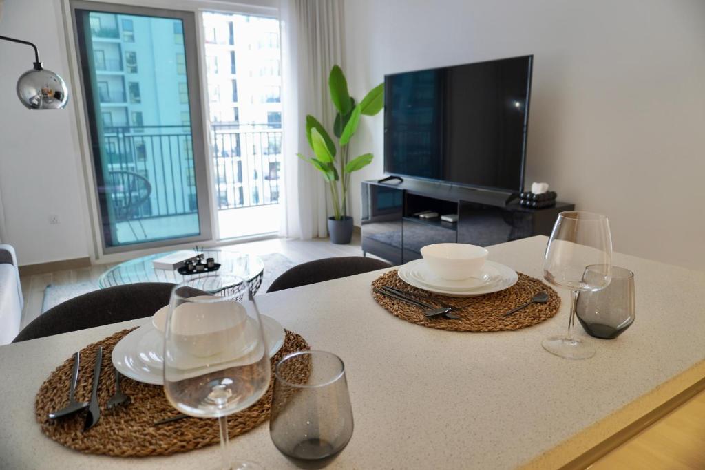 a table with glasses and plates and a television at Modern 1BR Yas Island Pool, Gym, Parking in Abu Dhabi
