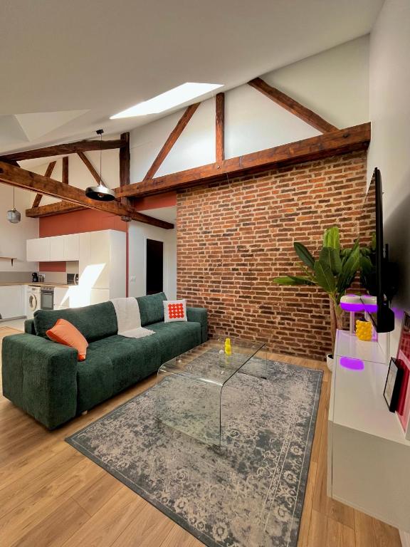 a living room with a green couch and a brick wall at Appartement Zola in Troyes