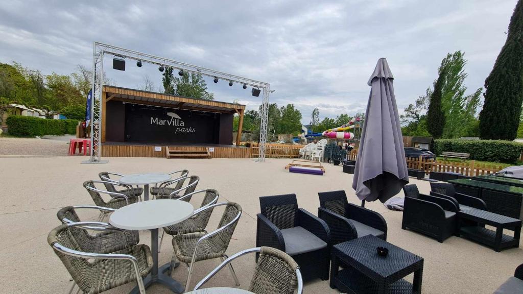 une table et des chaises avec une scène et un parasol dans l'établissement Mobil Home au calme Camping 4 Cadenet, à Cadenet