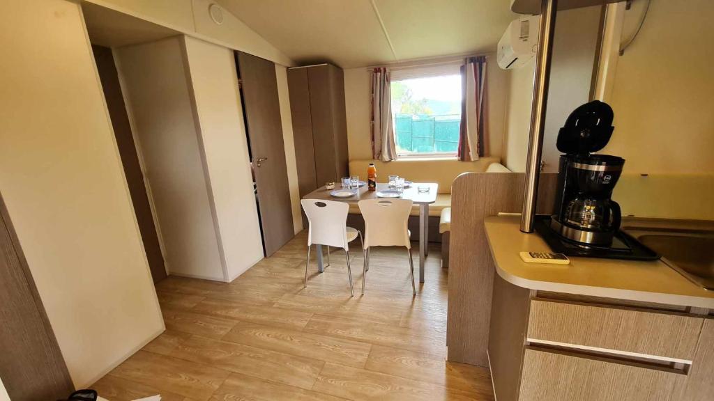 une cuisine avec une table et des chaises dans une pièce dans l'établissement Mobil Home au calme Camping 4 Cadenet, à Cadenet
