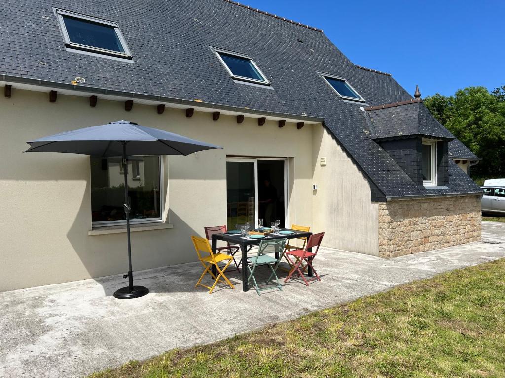 une table avec un parasol devant une maison dans l'établissement La Maison de Charlie, à Trégastel