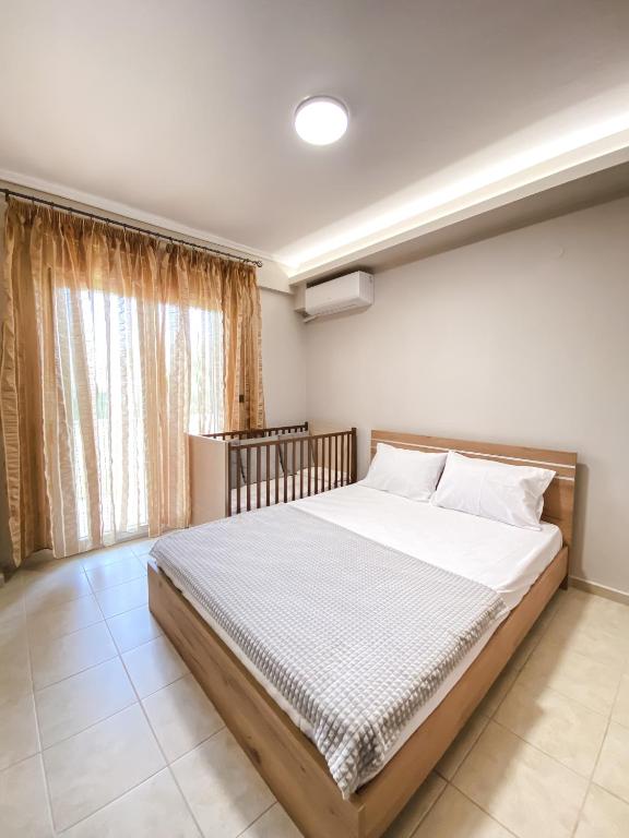 a bedroom with a bed with white sheets and a window at Olive Garden by Golden Host in Nea Moudania