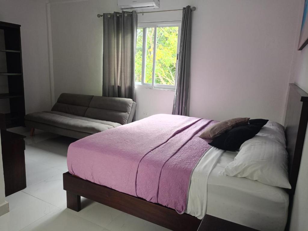 een slaapkamer met een bed, een bank en een raam bij HOKAB in Cenote Azul