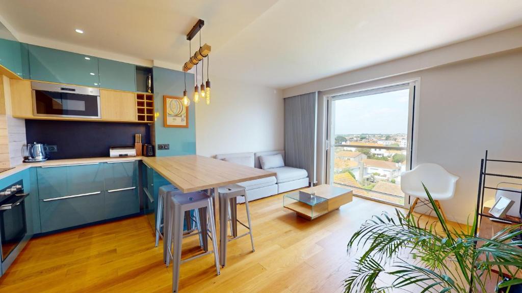 une cuisine avec des placards bleus et une grande fenêtre dans l'établissement Le Refuge du Marin, à Saint-Gilles-Croix-de-Vie