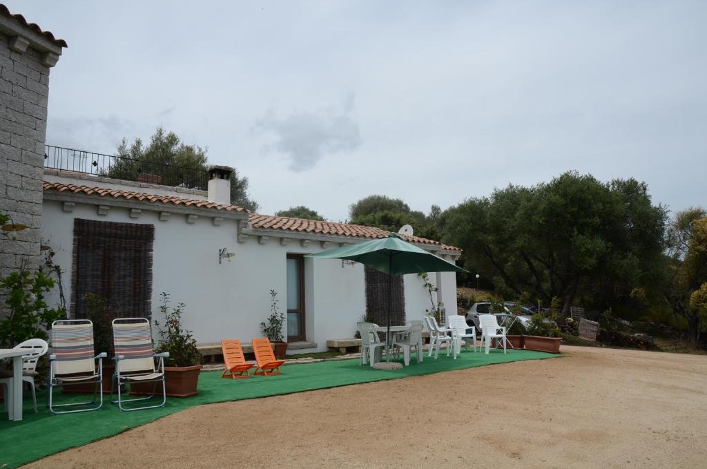 a house with chairs and an umbrella on a green lawn at Casa vista mare in San Teodoro