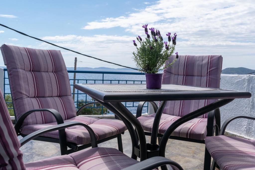 stół z krzesłami i wazon kwiatów na balkonie w obiekcie Sirius Apartments w mieście Neos Marmaras