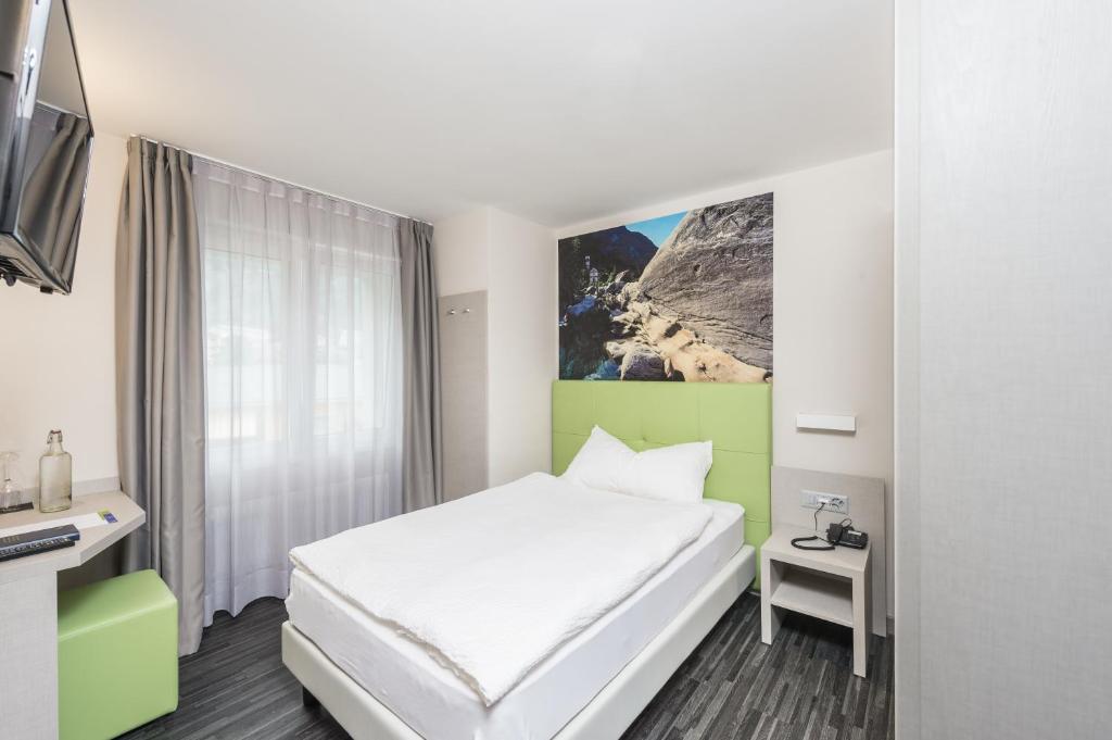 a hotel room with a white bed and a window at Adhhoc Hotel in Naters