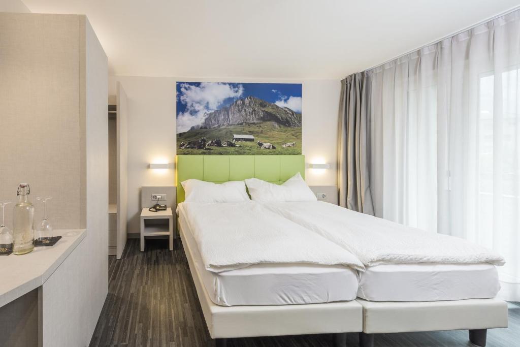 a bedroom with a white bed and a mountain at Adhhoc Hotel in Naters