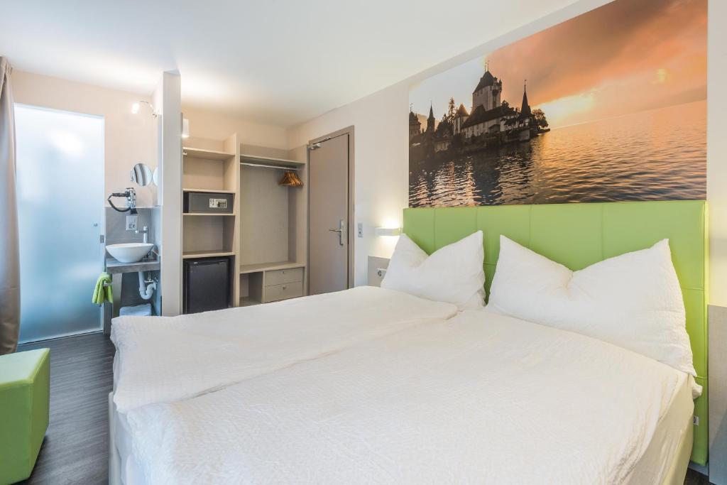 a bedroom with a white bed and a painting on the wall at Adhhoc Hotel in Naters
