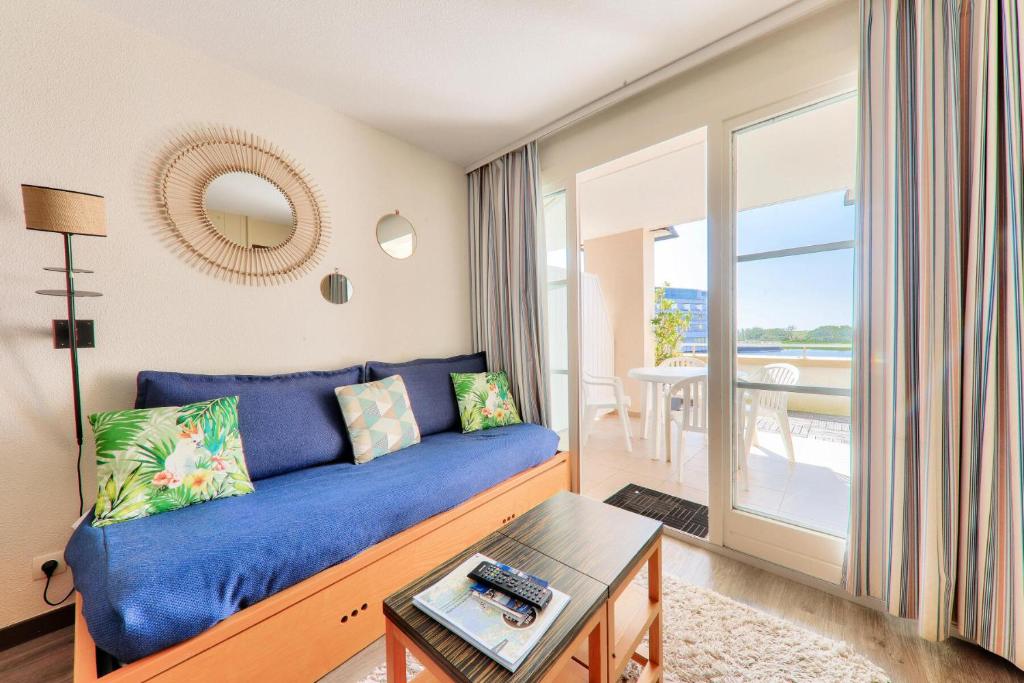 un salon avec un canapé bleu et une table dans l'établissement Résidence Port du Crouesty - maeva Home - Appartement 2 pièces 4 personnes - Confort MAE-8431, à Arzon