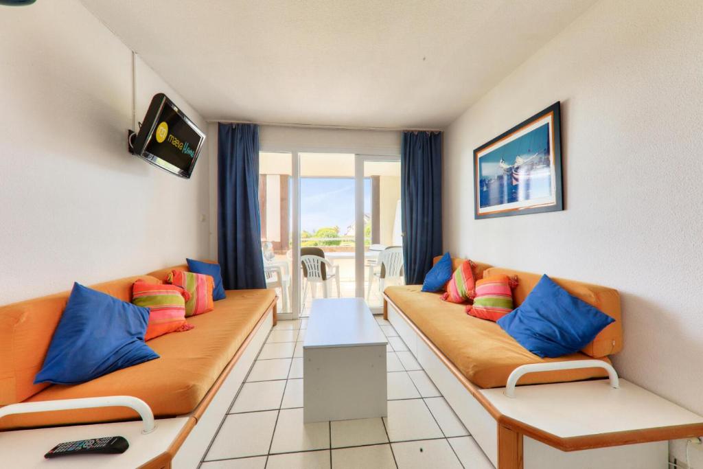 un salon avec deux canapés orange avec des coussins colorés dans l'établissement Résidence Port du Crouesty - maeva Home - Appartement 2 pièces 4 personnes vue mer - Confort MAE-0611, à Arzon