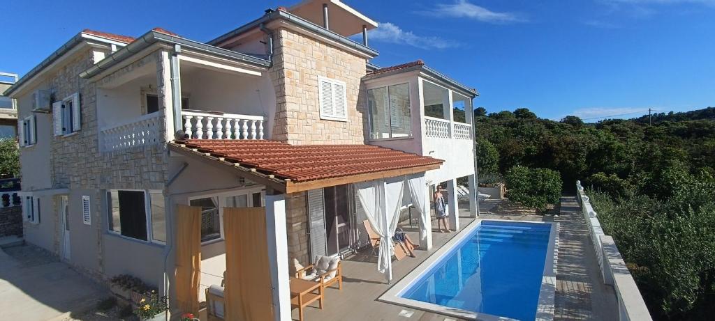 a house with a swimming pool in front of it at Apartments Solta in Nečujam